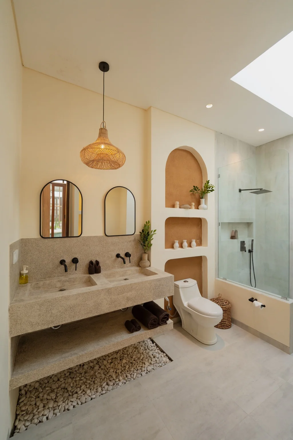 Homesafe Villas bathroom with a double stone vanity, arched mirrors and a glass shower