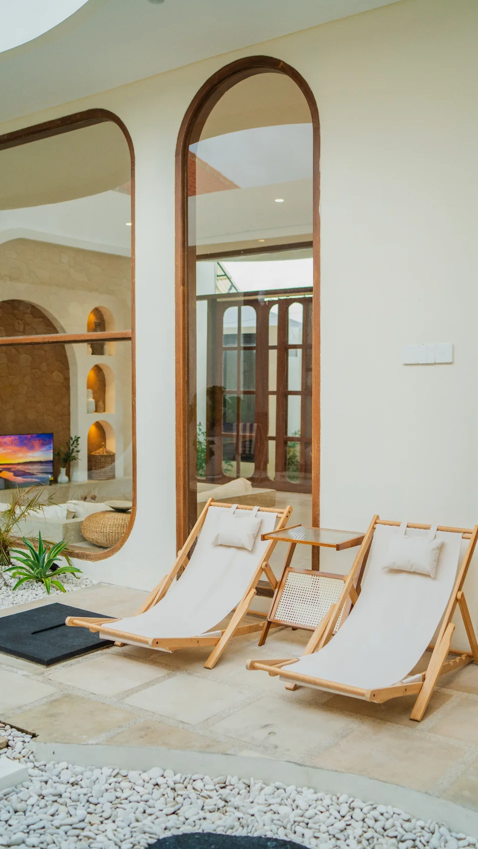 Courtyard loungers beside arched windows opening onto the cream living room at Homesafe Villas