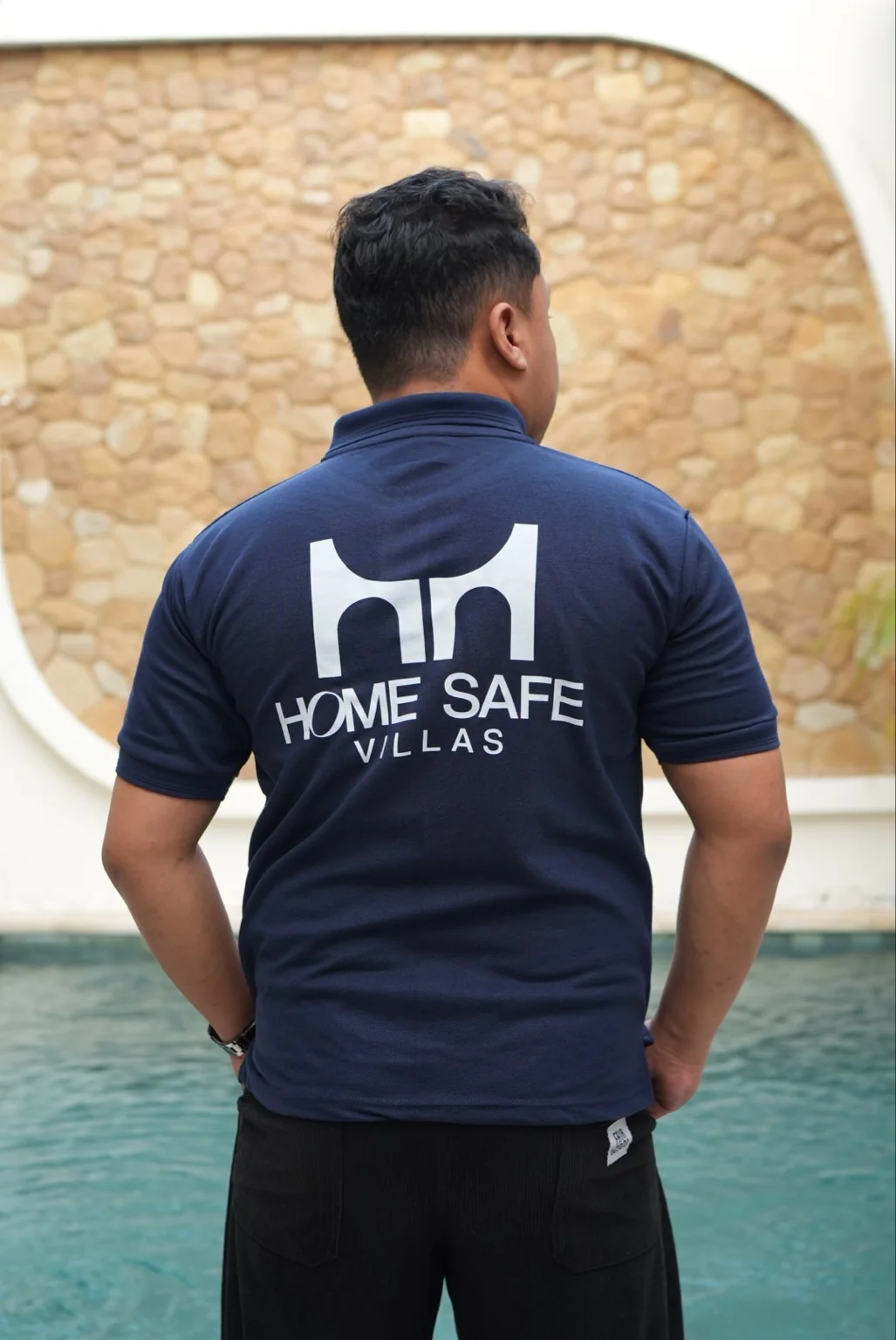 Homesafe Villas team member wearing a navy branded uniform beside the villa pool